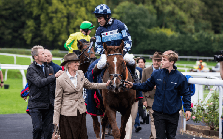 Champion Jockey Richard Johnson riding a horse surrounded by team members