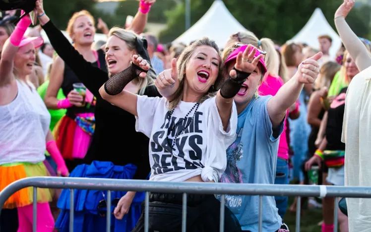 Two racegoer in fancy dress sing and dance to live music at Chepstow Races