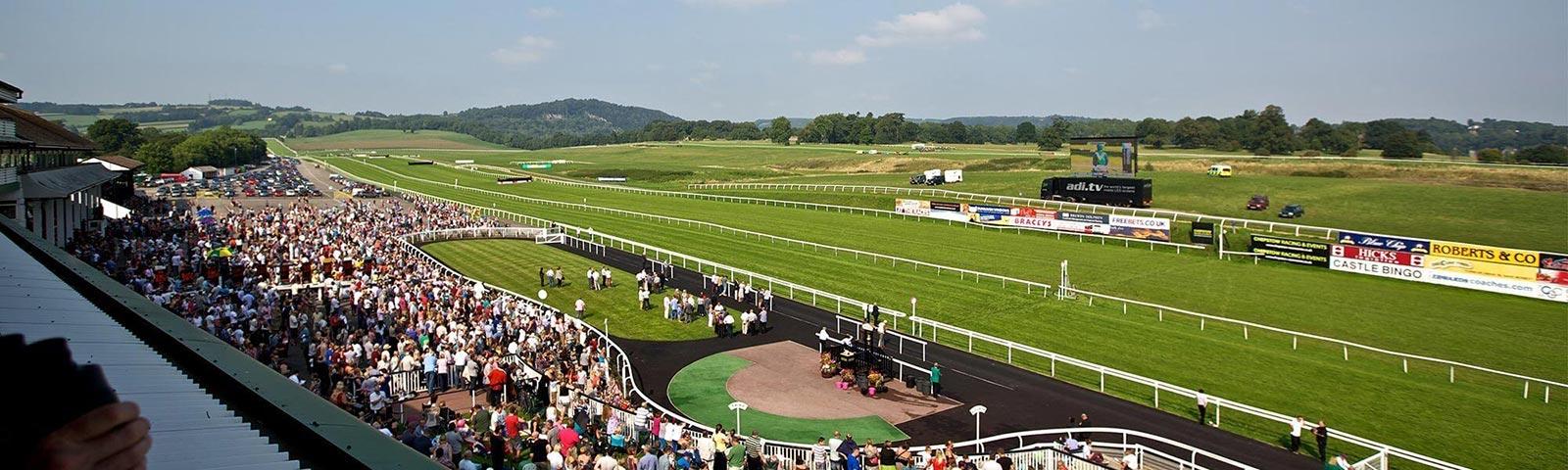 View of the track at Chepstow Racecourse during a race meeting with crowds watching.