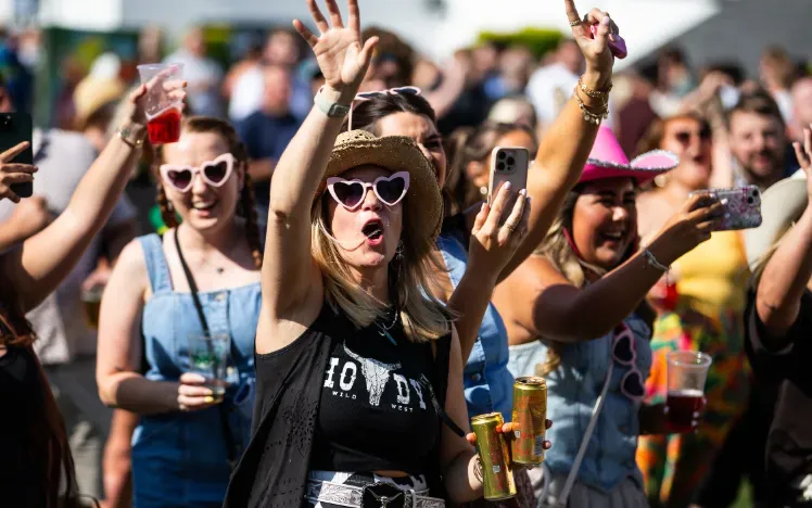 Racegoers dressed for a country theme at Chepstow races dance to the music