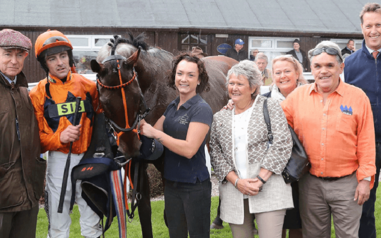 A racing team pose with their thoroughbred.