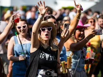 Racegoers dressed for a country theme at Chepstow races dance to the music