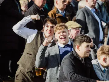Men in suits in the crowd cheering at Chepstow Races