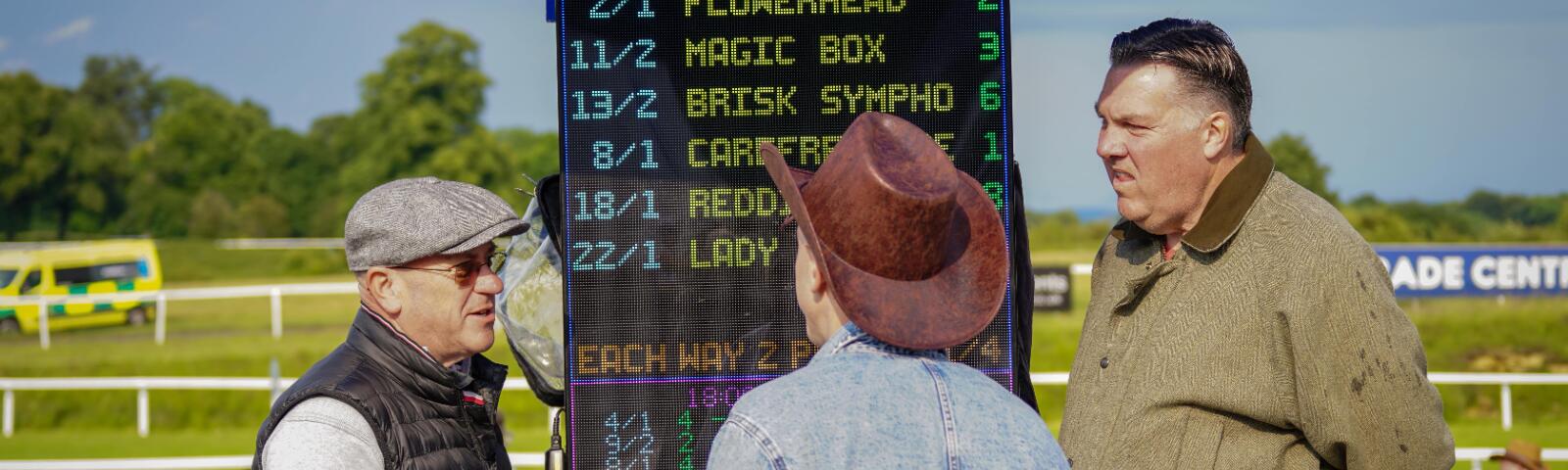 A racegoer at Chepstow studies the bookmaker boards and chats with them