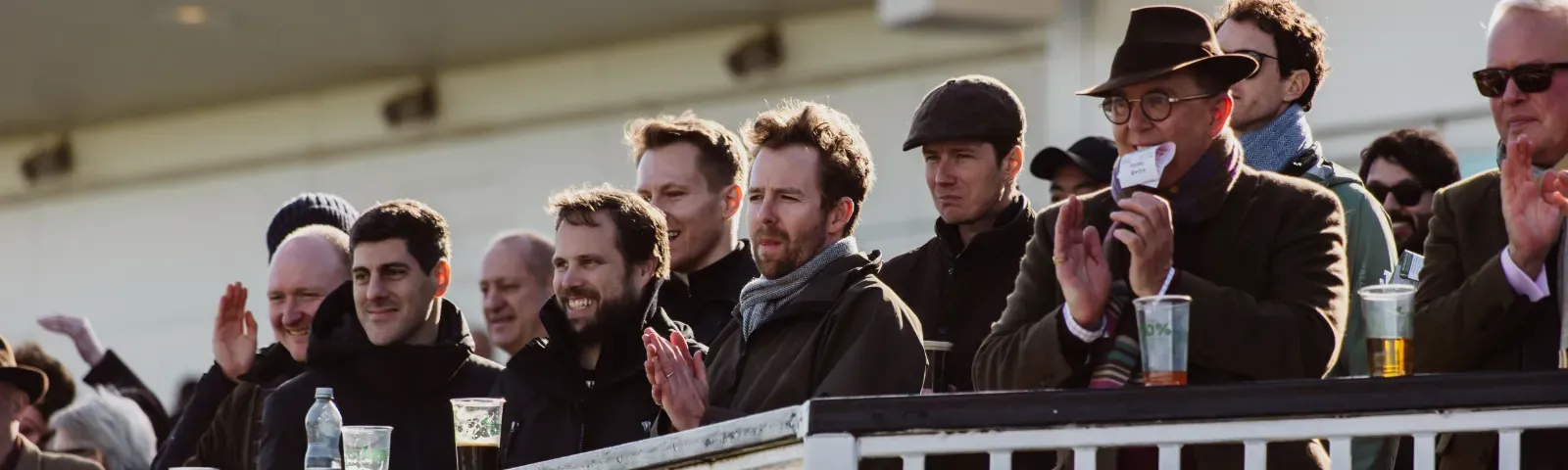 Four jockeys in colorful silks walking down the Chepstow Racecourse trackside walkway before a race