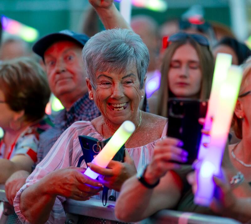A lady holding a large glow stick smiling widely during the entertainment at Chepstow Races