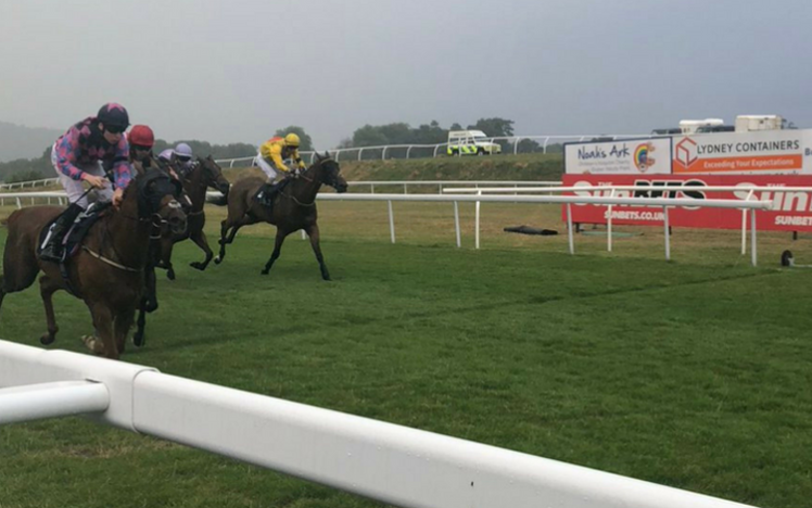 Four horses and Jockeys charge past the winning post at Chepstow Racecourse.