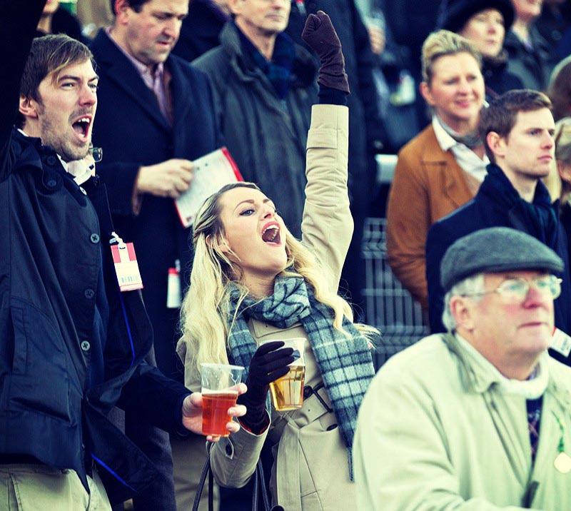 A woman in the crowd cheering on while watching racing.