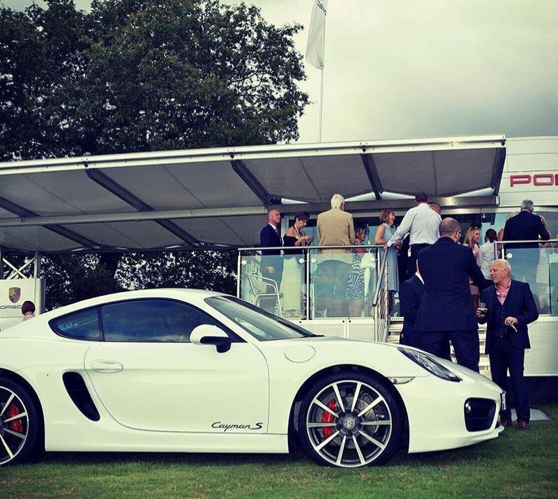 A Porsche Cayman S sits outside a Porsche sponsor area at Chepstow Racecourse.