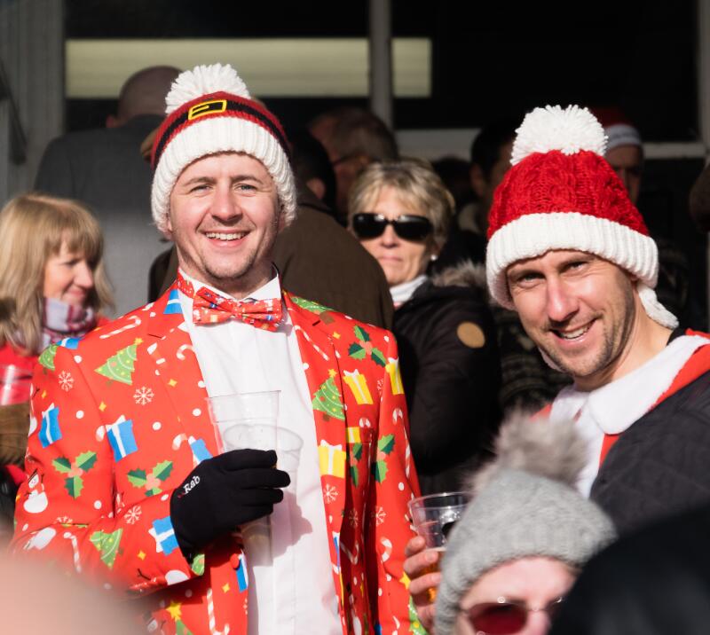 Two race goers in festive fancy dress and Christmas hats