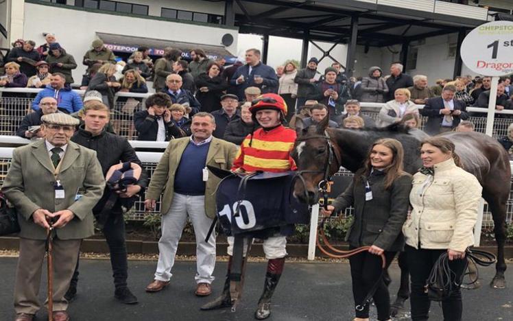 A winning team celebrates victory with their horse.