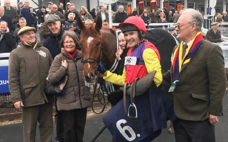 A winning team celebrate with their thoroughbred