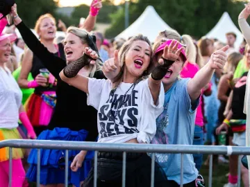 Two racegoer in fancy dress sing and dance to live music at Chepstow Races