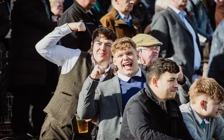Men in suits in the crowd cheering at Chepstow Races