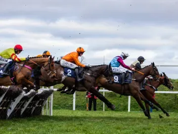 Horses jump elegantly over a jump at Chepstow Races