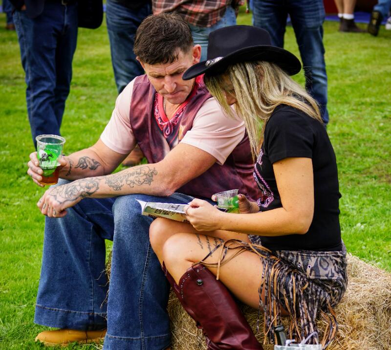 A couple at Chepstow Racecourse sit on a hay bale and study the race card